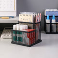 Black metal mesh organiser shown on a desk with notebooks and stationery
