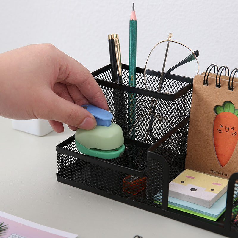 Close-up of black metal mesh desk organiser holding pencils, notepad and small stationery